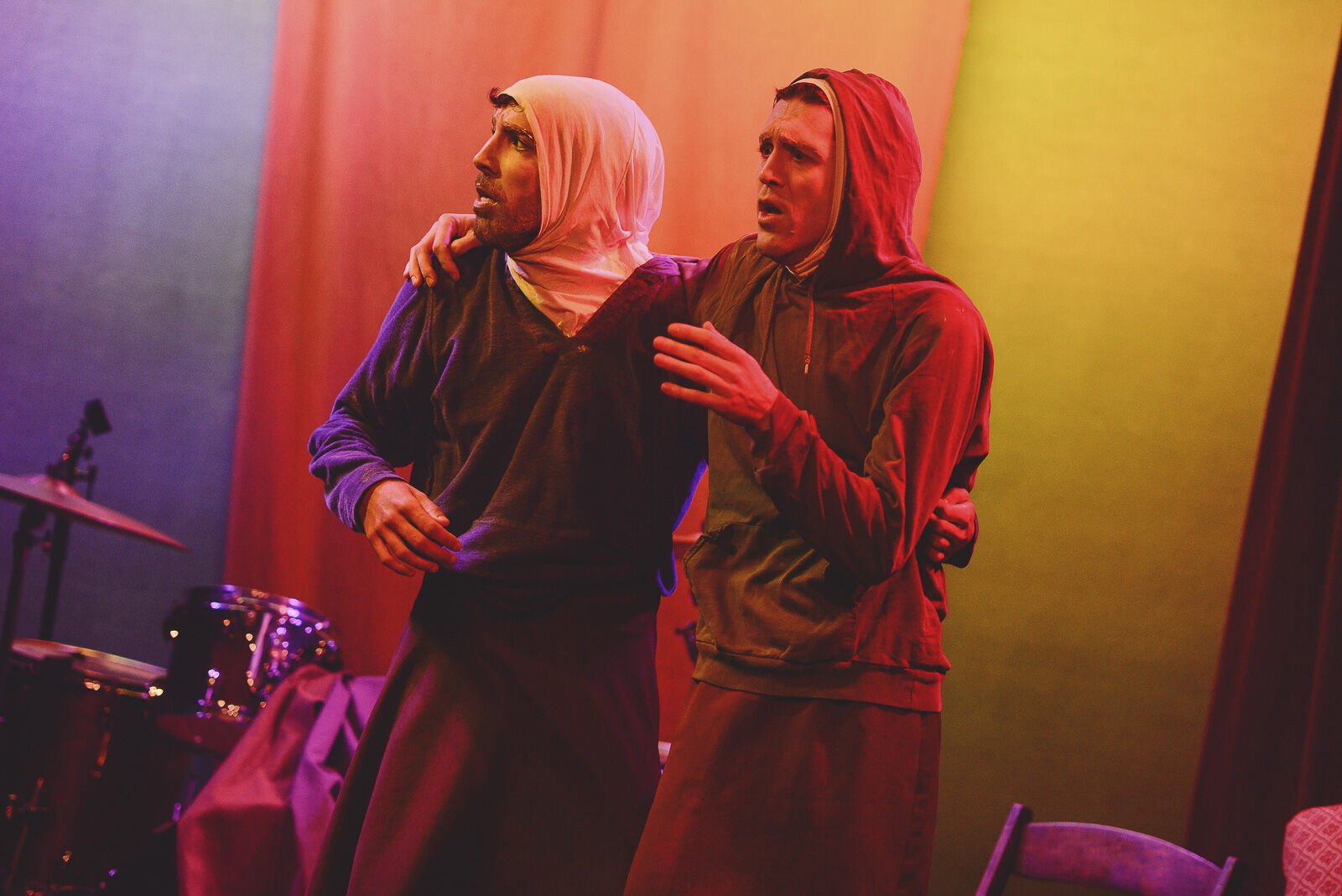 two men wrapped in robes embrace each other in distress