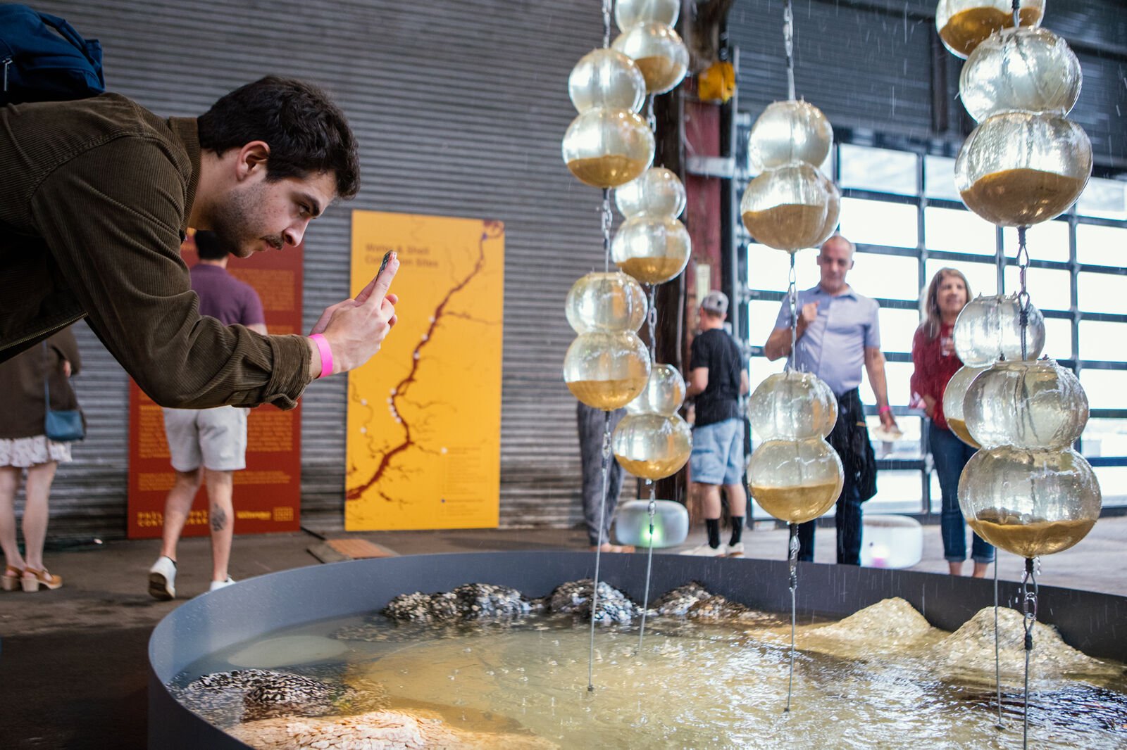 Guest taking a photo of fountain. The basin features pearl blankets sewn from pearl buttons made from reclaimed mussel shells.